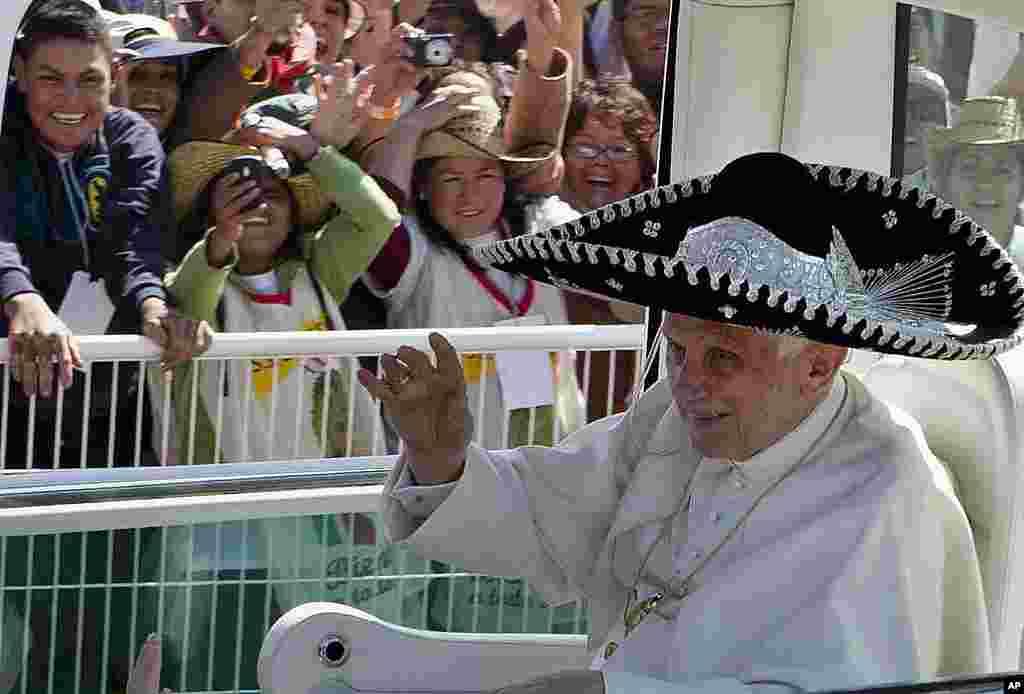 Đức Giáo Hoàng Benedicto vẫy chào từ xe riêng, đầu đội một chiếc nón rộng vành kiểu Mexico khi đến nơi cử hành thánh lễ ở Công trường Bicentennial gần Silao, Mexico, ngày 25 tháng 3 năm 2012. (AP) 