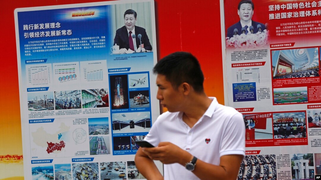 2018年8月22日，北京地铁站外的政府宣传广告牌宣传中国国家主席习近平和中国的经济成就，一名男子站在旁边。