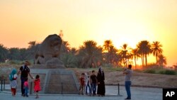 People stand near the Lion of Babylon at the archaeological site of Babylon, Iraq, July 5, 2019. The UNESCO World Heritage Committee named the historic city of Babylon a World Heritage Site.