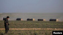 FILE - Trucks move near Baghouz, Deir el-Zour province, Syria, Feb. 19, 2019. 