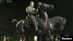 Para pekerja menyingkirkan patung-patung Robert E. Lee, komandan pasukan Konfederasi yang mendukung perbudakan dalam Perang Saudara Amerika dan patung Thomas "Stonewall" Jackson, seorang jenderal Konfederasi dari Wyman Park di Baltimore, 16 Agustus 2017.