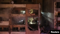 Ljudi stoje kod oštećene zgrade nakon eksplozije u predgrađu Bejruta Dahiyeh