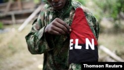 FILE - A rebel of Colombia's Marxist National Liberation Army shows his armband while posing for a photograph, in the northwestern jungles, Colombia Aug. 31, 2017. 