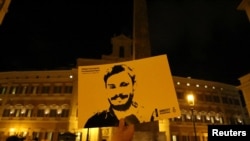 FILE - A man holds a placard during a vigil in memory of Giulio Regeni, who was found murdered in Cairo, Egypt, in January of 2016, in downtown Rome, Italy, Jan. 25, 2017.