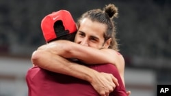 Gianmarco Tamberi, of Italy, embraces fellow gold medalist Mutaz Barshim, of Qatar, after the final of the men's high jump at the 2020 Summer Olympics in Tokyo, August 1, 2021.