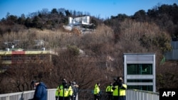 TOPSHOT - Police officers stand guard outside of impeached South Korea president Yoon Suk Yeol's residence (back) in Seoul on Jan. 2, 2025.