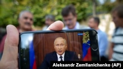 RUSSIA -- A man watches on his smartphone Russian President Vladimir Putin's televised address on pension reform, in Moscow, August 29, 2018