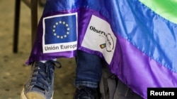 FILE - A member of the LGBT movement holds a flag with signs of the European Union and LGBT rights in La Paz, Bolivia, Dec. 11, 2020. 