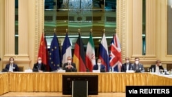 FILE - EEAS Deputy Secretary-General Enrique Mora and Iranian Deputy at Ministry of Foreign Affairs Abbas Araghchi wait for start of a meeting of JCPOA Joint Commission in Vienna, Apr. 6, 2021. (EU Delegation in Vienna/via Reuters)