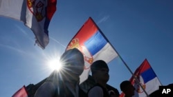 Orang-orang mengibarkan bendera Serbia selama pertemuan "Majelis Seluruh Serbia" di Beograd, Serbia, Sabtu, 8 Juni 2024. (Foto: AP)