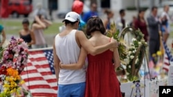 A couple spends a quiet moment at a makeshift memorial honoring the victims of the Pulse nightclub mass shooting in Orlando, Fla., June 20, 2016.