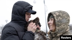 Illija Muzika (29) i Alina Panina (27), ukrajinski graničari i bivši ratni zarobljenici igraju se sa njenim psom Roksi, nakon što su oboje pušteni iz zatočeništva, 23. januara 2024. (Foto: Rojters/Valentyn Ogirenko)