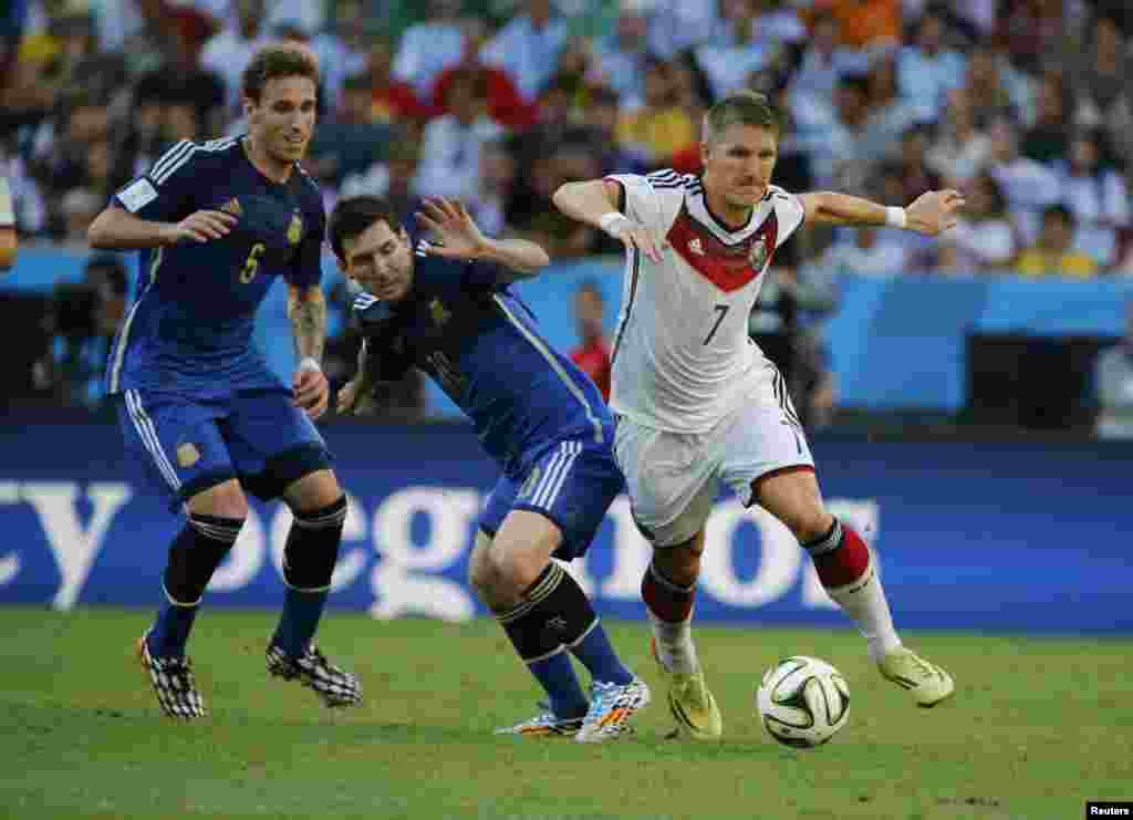 Argentina's Lucas Biglia and Lionel Messi challenge Germany's Bastian Schweinsteiger during their 2014 World Cup final at the Maracana stadium in Rio de Janeiro July 13, 2014.