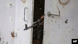 The barrel of an Indian paramilitary soldier's weapon is seen between partially closed doors of an armored vehicle as they drive towards the site of an operation in Awantipora area on May 6, 2020. 