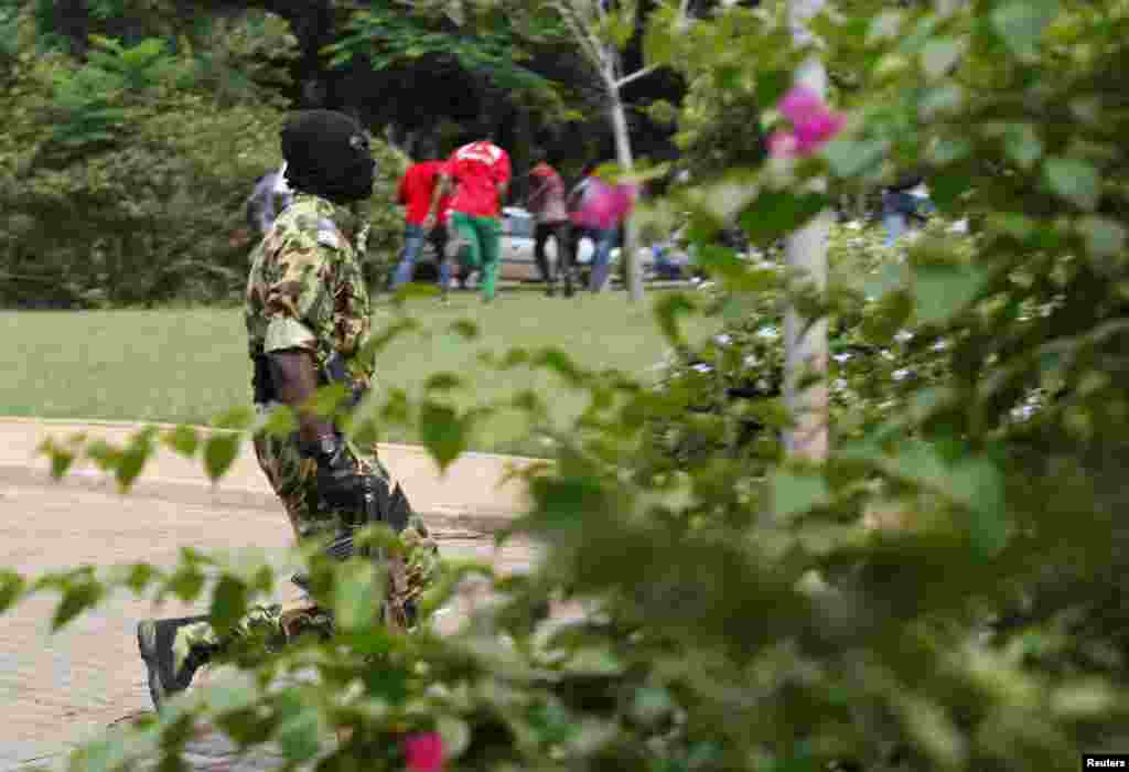 A presidential guard arrives as protesters run away at the Laico hotel in Ouagadougou, Burkina Faso, September 20, 2015. Pro-coup demonstrators in Burkina Faso on Sunday invaded the hotel due to host talks aimed at hammering out the details of a deal to r