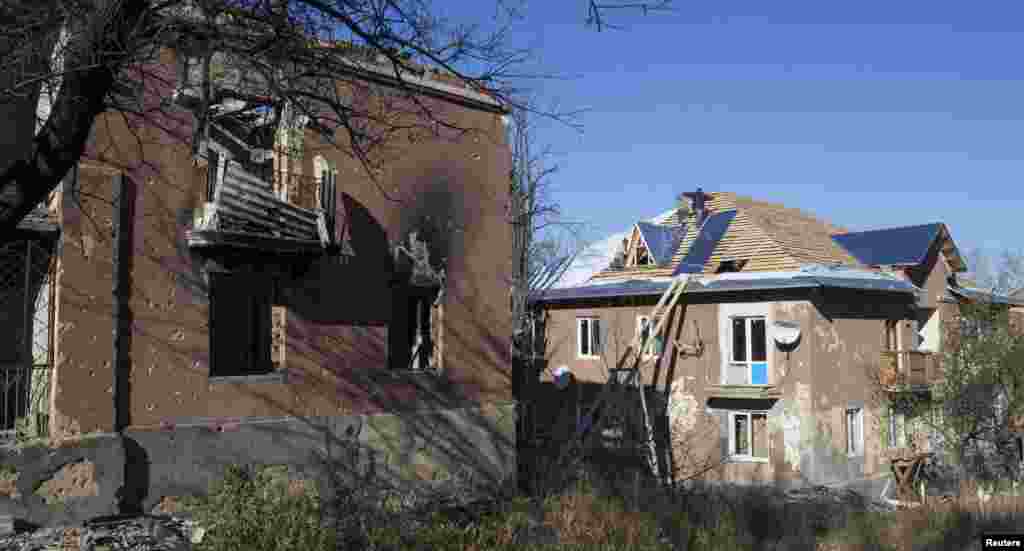 Workers repair the roof of a house damaged by recent shelling in the village of Semyonovka, near Slovyansk, eastern Ukraine, Oct. 27, 2014. 