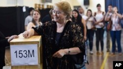 In this photo released by Presidencia of Chile, Chilean President Michelle Bachelet casts her vote during presidential elections in Santiago, Nov. 19, 2017.