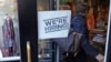 FILE - In this May 18, 2016, file photo, a woman passes a "We're Hiring!" sign while entering a clothing store in the Downtown Crossing of Boston. 