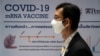A man wearing a face mask stands next to a board showing the progress of developing an mRNA type vaccine candidate for COVID-19 during a news conference at the National Primate Research Center of Chulalongkorn University, June 22, 2020. 