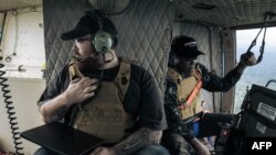 FILE—Caleb Weiss (L) of the American group The Bridgeway Foundation, and Colonel Udju of the armed forces of DRC broadcast messages from a helicopter over the strongholds of the ADF urging them to surrender, on May 8, 2024, over Beni territory, North Kivu , eastern DRC. 