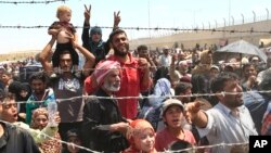 FILE - Syrian refugees gather at the Turkish border as they flee intense fighting in northern Syria between Kurdish fighters and Islamic State militants in Akcakale, southeastern Turkey, June 15, 2015.