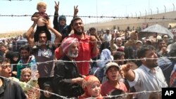 FILE - Syrian refugees gather at the Turkish border as they flee intense fighting in northern Syria between Kurdish fighters and Islamic State militants in Akcakale, southeastern Turkey, June 15, 2015.