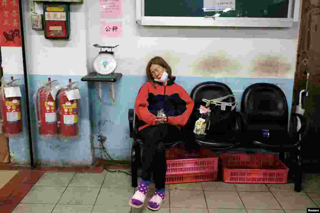 Una mujer descansa con su máscara facial retirada en medio de la propagación de la enfermedad COVID-19 en un mercado en Taipei, Taiwán.