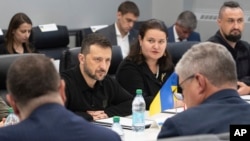 In this photo provided by the U.S. Army, Ukrainian President Volodymyr Zelenskyy, center, listens while visiting the Scranton Army Ammunition Plant in Scranton, Pennsylvania, Sept. 22, 2024.