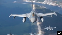 A Romanian Air Force F- 16s military fighter jet, in front, and a Portuguese Air Force F- 16s military fighter jets participating in NATO's Baltic Air Policing Mission operate over the Baltic Sea, Lithuanian airspace, Monday, May 22, 2023. (AP Photo/Mindaugas Kulbis)