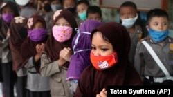 Children wear masks in the wake of the outbreak of a new coronavirus at a kindergarten in Jakarta, Indonesia, Thursday, March 5, 2020. Parents are deciding how to discuss the virus with their children.