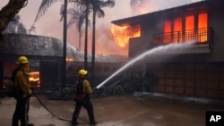 Firefighters hose down flames as the Palisades Fire reaches a residence in the Pacific Palisades neighborhood of Los Angeles, Jan. 7, 2025. 