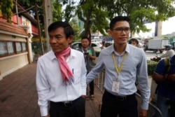 FILE - Journalists Uon Chhin, left, and Yeang Sothearin arrive at the municipal court, in Phnom Penh, Oct. 3, 2019.