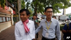 FILE - Journalists Uon Chhin, left, and Yeang Sothearin arrive at municipal court in Phnom Penh, Oct. 3, 2019.