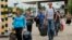 People carry their belongings as they walk to cross the border into Russia at the Ukrainian-Russian border checkpoint in Izvaryne, Luhansk region, eastern Ukraine Thursday, June 26, 2014