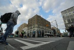 Pedestrians wear personal protective equipment as they cross Main Street in the Flushing section of the Queens borough of New York on April 1, 2020.