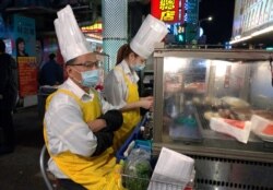 Two vendors wear face masks and wait for customers at a night market in Taipei, Taiwan, Thursday, Feb. 6, 2020.