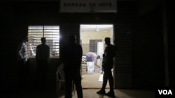 A guard and several bystanders are seen outside as votes are being counted at a polling station in Ouagadougou, Burkina Faso, November 29, 2015. (Photo - E. Iob/VOA)