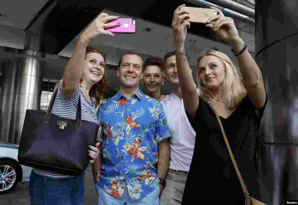 Russian Prime Minister Dmitry Medvedev poses for pictures with tourists while sightseeing during his visit to Kuala Lumpur, Malaysia, for the East Asia Summit (EAS).