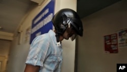 Samson D'Souza, face covered with a helmet arrives at the Goa State Children's Court in Panaji, April 5, 2010.