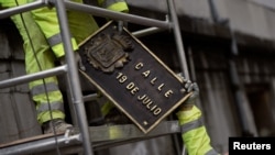 FILE - Workers remove street plates with Franco era references, in appliance to Spain's law of Historical Memory which forbids public places or entities to be named with references to Spain's former dictatorship, Oviedo, Spain, April 13, 2018.