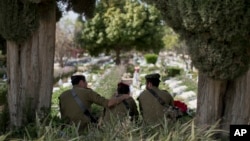 Israeli soldiers visit in Kiryat Shaul military cemetery on the eve of Memorial Day, in Tel Aviv, April 17, 2018. Israel marks the annual Memorial Day in remembrance of soldiers who died in the nation's conflicts, beginning at dusk Tuesday and running until Wednesday evening.