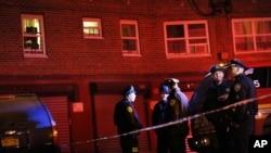 FILE - Emergency officials gather near the site where two police officers were shot in the Bronx section of New York.