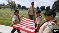 Boy Scouts from the Long Beach troop prepare a U.S. flag besides the graves of war veterans during the annual 'Flag Placement ceremony' to honor the fallen for Memorial Day at the Los Angeles National Cemetery, Calif., on May 25, 2019.