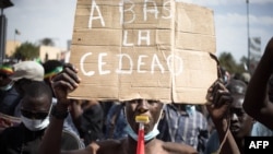 FILE - A demonstrator holds a sign reading "Down with ECOWAS (Economic Community of West African States)," during a mass demonstration to protest against sanctions imposed on Mali and the Junta, by the regional grouping, in Bamako on January 14, 2022.