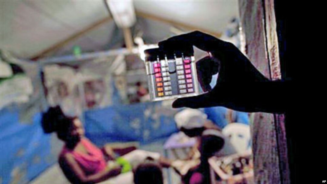An employee of Haiti's Ministry of Health shows a device that measures the level of chlorine in the water consumed by earthquake survivors at a refugee camp in Port-au-Prince, 25 Oct 2010