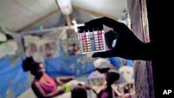 An employee of Haiti's Ministry of Health shows a device that measures the level of chlorine in the water consumed by earthquake survivors at a refugee camp in Port-au-Prince, 25 Oct 2010