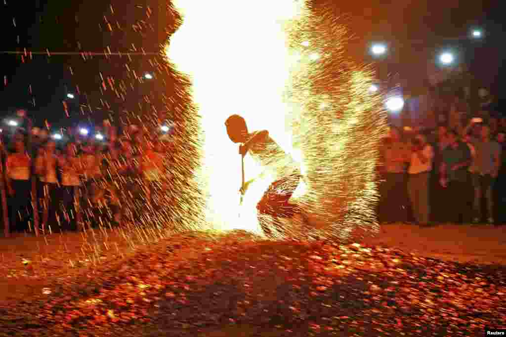 A man runs through burning charcoal barefooted as he participates in a traditional ritual called "Lianhuo", or "fire walking", in Pan'an county, Zhejiang province, China, Sept. 17, 2014.