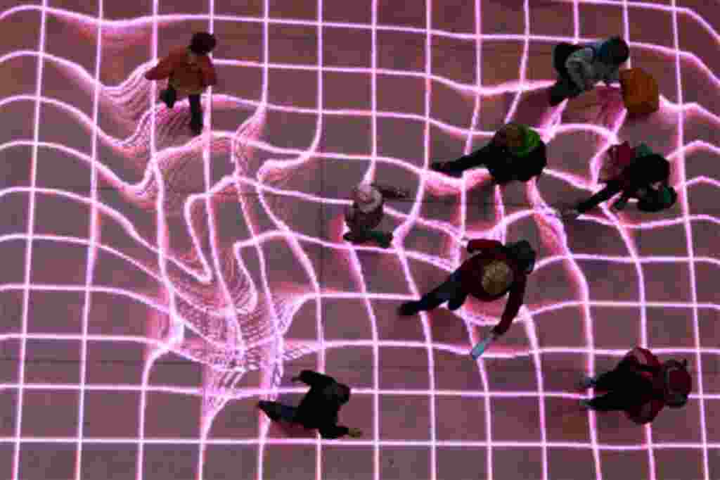 People walk over the interactive installation "Onskebronn", Norwegian for wishing well, at A central station in Berlin, Germany, Thursday, Oct. 14, 2010. The moving paths of visitors are followed on that LED-platform and retraced as reprocessed projection