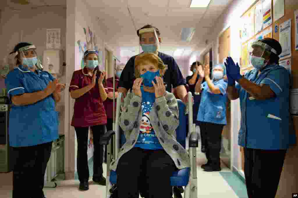 Margaret Keenan, 90, is applauded by staff as she returns to her ward after becoming the first patient in the UK to receive the Pfizer-BioNTech COVID-19 vaccine, at University Hospital, Coventry, England, Dec. 8, 2020. 