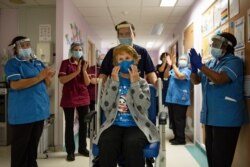 Margaret Keenan, 90, is applauded by staff as she returns to her ward after becoming the first patient in the UK to receive the Pfizer-BioNTech COVID-19 vaccine, at University Hospital, Coventry, England, Dec. 8, 2020.